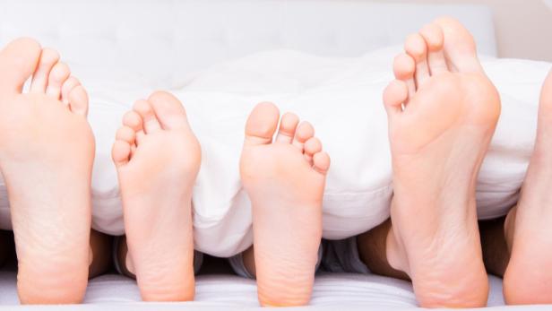 Gesunde Füße lugen unter einer Bettdecke hervor