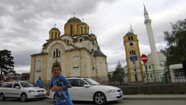 Ein lächelnder Junge rennt vor einer Kirche und einem Minarett vorbei.