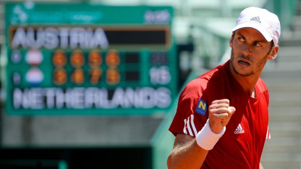 Ein Tennisspieler jubelt vor einer Anzeigetafel mit den Aufschriften „Austria“ und „Netherlands“.