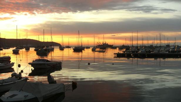 Boote liegen bei Sonnenuntergang in einem Hafen.