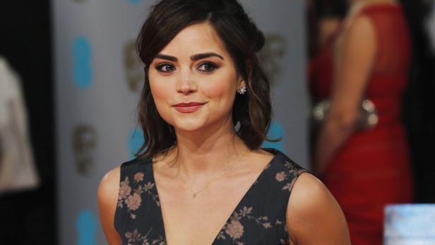 Jenna Coleman lächelt auf einem Event in einem floralen Kleid.