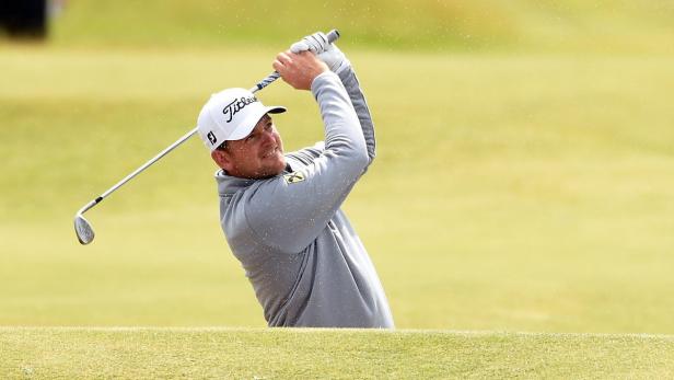 Ein Golfspieler schlägt einen Ball aus einem Bunker.