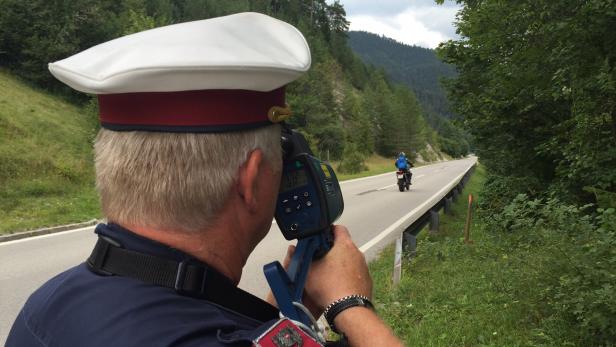 Ein Polizist misst die Geschwindigkeit eines Motorradfahrers.