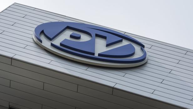Das blaue PZ-Logo ist an einer Fassade mit horizontalen Metallplatten angebracht.