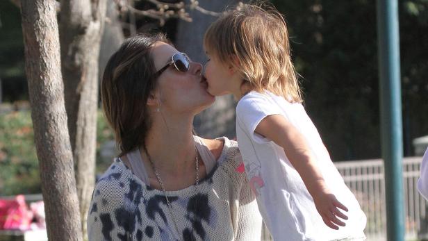 Eine Mutter küsst ihr Kind im Freien auf den Mund.