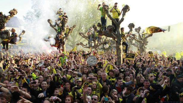 Eine große Menschenmenge, viele in gelb-schwarzen Borussia Dortmund-Trikots, feiert auf einem Platz.