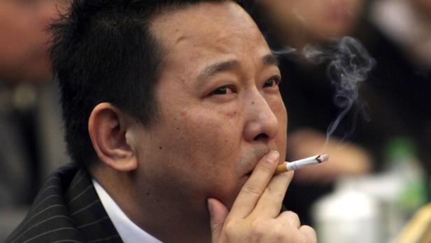 Ein Mann im Anzug raucht eine Zigarette.