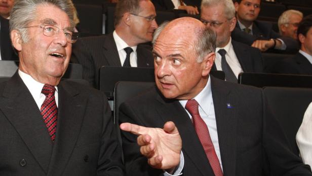 Zwei Männer in Anzügen sitzen nebeneinander und unterhalten sich.