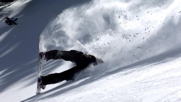 Ein Snowboarder stürzt im Tiefschnee.