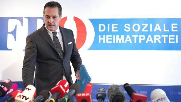Ein Mann im Anzug steht vor Mikrofonen und dem Logo der FPÖ.