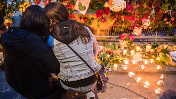 Well wishers comfort each other as they place flowers at a makeshift memorial outside a department store in Stockholm on April 8, 2017. \r 4 people died and 15 was injured when a hijacked truck plunged into a crowd in a pedestrian shopping area in the Swedish capital on April 7, 2017. / AFP PHOTO / Odd ANDERSEN