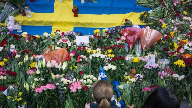 TOPSHOT - Women lay flowers on April 9, 2017 at a makeshift memorial near the point where a truck drove into a department store in Stockholm, Sweden.\r Four people died and fifteen were injured when a truck plunged into a crowd at a busy pedestrian street in the Swedish capital on April 7, 2017. / AFP PHOTO / Jonathan NACKSTRAND