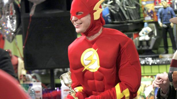 Ein Mann verkleidet als „The Flash“ hält eine goldene Trophäe in der Hand.