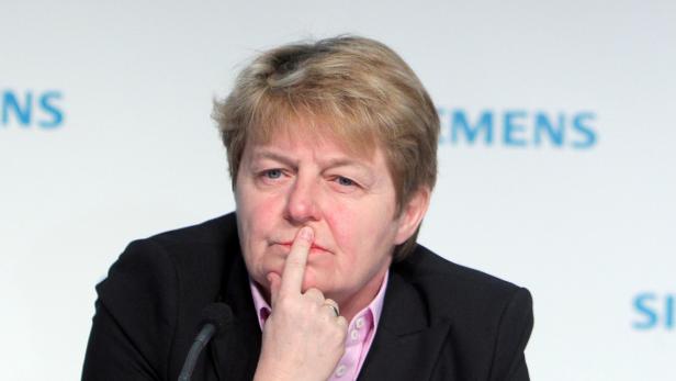 Eine Frau in einem schwarzen Blazer denkt nach, den Finger an die Lippe gelegt.