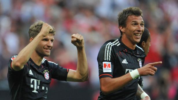Thomas Müller und ein weiterer Bayern-Spieler jubeln auf dem Fußballfeld.