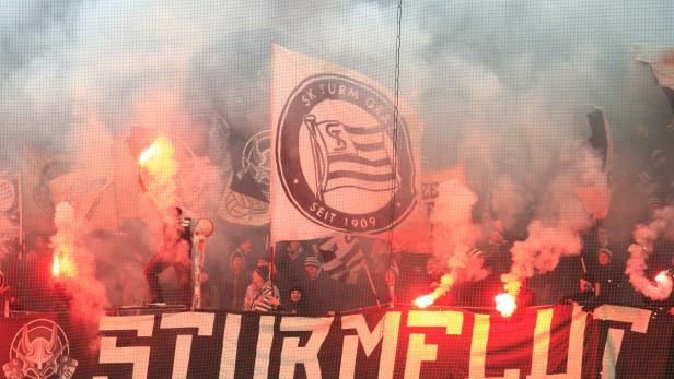 Fans des SK Sturm Graz zünden während eines Spiels bengalische Feuer.