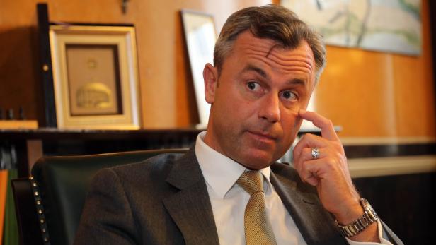 Ein Mann im Anzug sitzt und berührt nachdenklich sein Gesicht.