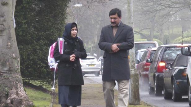 Malala Yousafzai geht mit ihrem Vater auf einer Straße entlang.