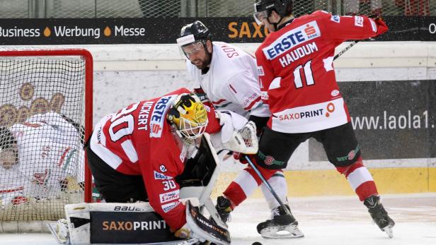 Ein Eishockeyspieler versucht, den Puck am Torwart vorbei ins Tor zu schießen.