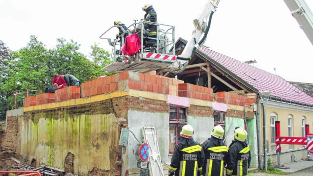 Die Feuermauer zum Nachbarhaus war plötzlich eingestürzt. Mit dem Kran wurden die verletzten Bauarbeiter geborgen