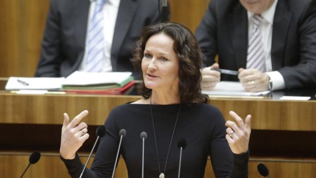 Eine Frau spricht vor Mikrofonen bei einer Veranstaltung.
