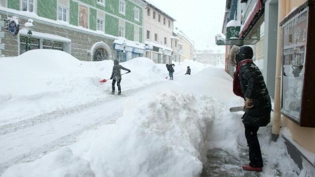 Menschen schaufeln Schnee auf einer verschneiten Straße in einer Stadt.