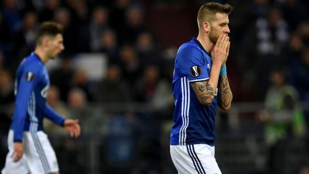 Ein Fußballspieler in blau-weißem Trikot hält die Hände vors Gesicht.