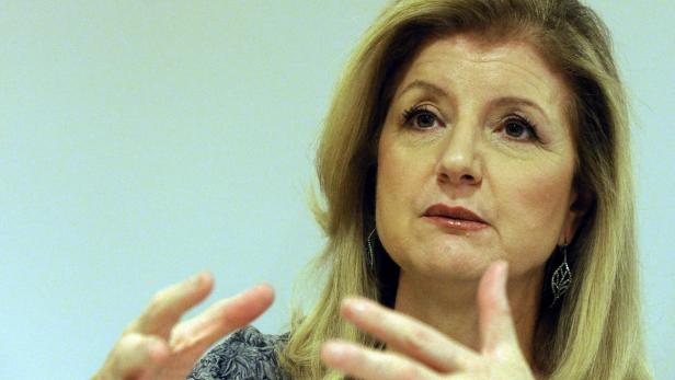 Eine Frau mit blonden Haaren gestikuliert vor einem hellen Hintergrund.