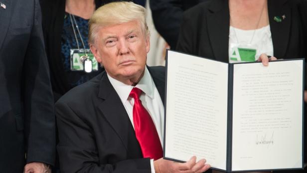 Donald Trump hält ein aufgeschlagenes Dokument in die Kamera.