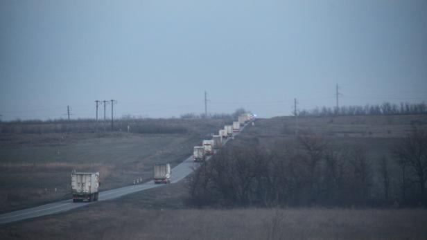 Eine Kolonne von Lastwagen fährt auf einer Landstraße entlang.