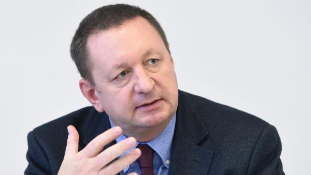 Ein Mann in Anzug und Hemd gestikuliert mit der Hand.