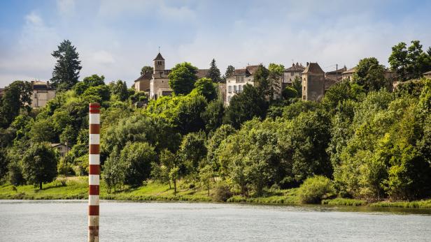 Blick auf eine französische Stadt auf einem Hügel, gesehen von einem Fluss aus.