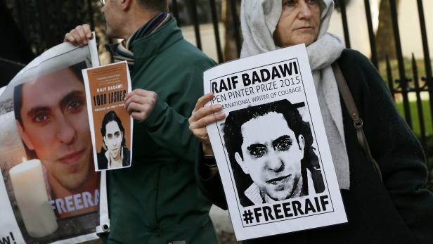 Menschen demonstrieren mit Plakaten für die Freilassung von Raif Badawi.