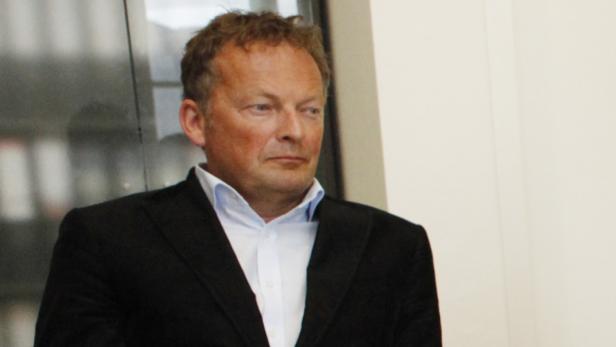 Ein Mann mit dunklem Sakko und hellem Hemd blickt zur Seite.