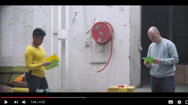 Eine Frau und ein Mann stehen in einem Raum und betrachten farbige Blätter.