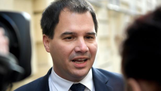 Ein Mann im Anzug spricht mit jemandem, der außerhalb des Bildes steht.