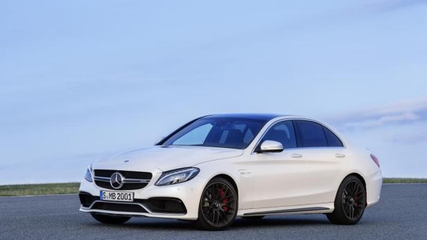 Ein weißer Mercedes-Benz C 63 AMG steht auf einer asphaltierten Fläche.