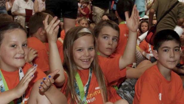 Eine Gruppe Kinder sitzt auf dem Boden und lächelt in die Kamera.