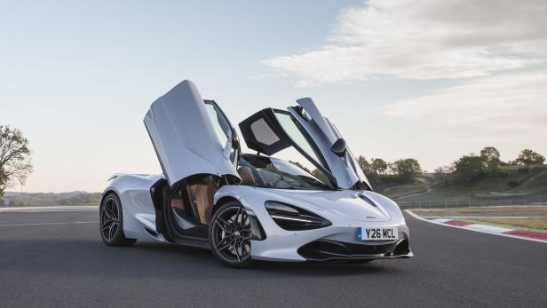 Ein silberner McLaren 720S mit geöffneten Flügeltüren steht auf einer Rennstrecke.