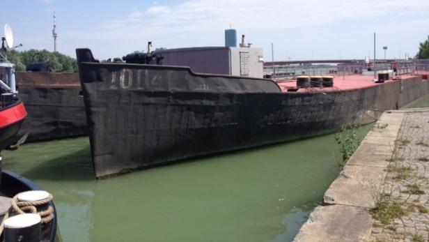 Ein großes, schwarzes Frachtschiff liegt an einem Kai.