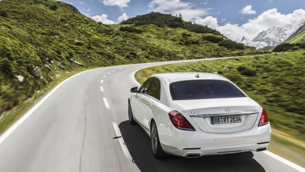 Ein weißer Mercedes-Benz fährt auf einer kurvenreichen Bergstraße.