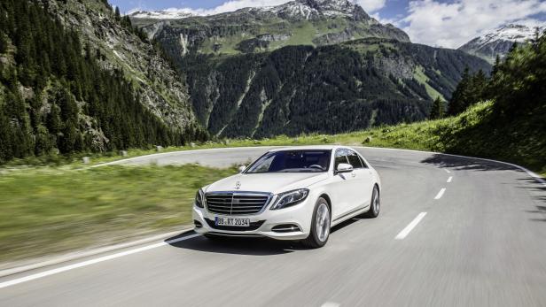 Ein weißer Mercedes-Benz fährt auf einer kurvenreichen Bergstraße.