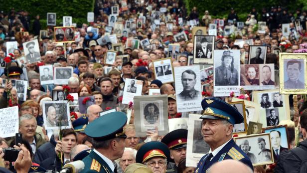 Angehörige versammelten sich vor dem Grab des unbekannten Soldaten in Kiew und hielten Fotos ihrer Verwandten, die im &quot;Großen vaterländischen Krieg&quot; gestorben sind hoch.