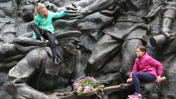 Kinder erklettern Geschichte: Zwei Bewohnerinnen Kiews auf einem Denkmal zum Zweiten Weltkrieg