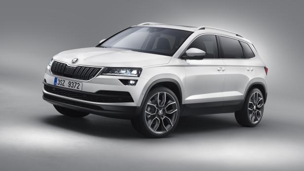 Ein weißer Škoda Karoq SUV vor einem grauen Hintergrund.