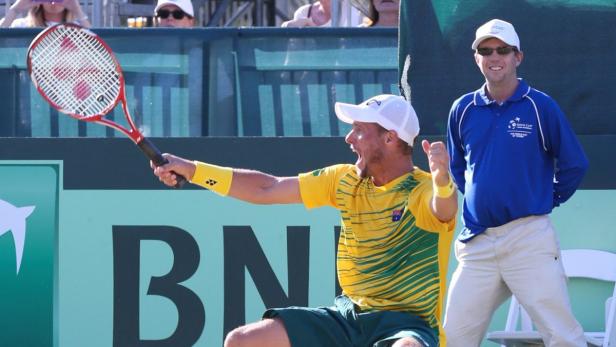 Ein australischer Tennisspieler jubelt mit erhobenem Schläger auf dem Platz.