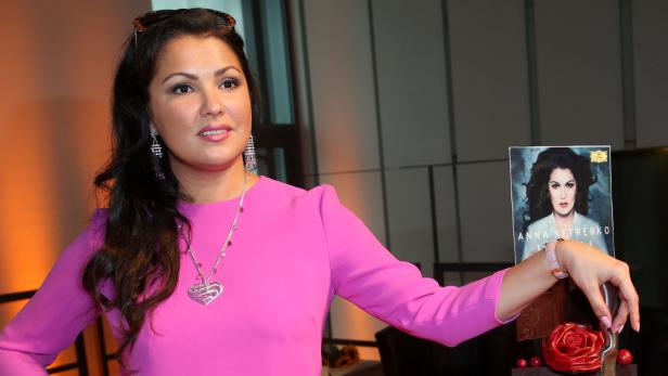 Anna Netrebko posiert neben einem Cover ihres Buches.