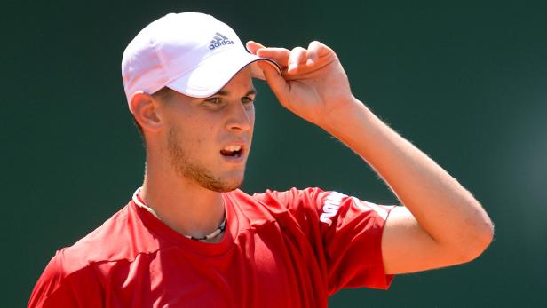 Dominic Thiem mit rotem T-Shirt und weißer Kappe auf einem Tennisplatz.