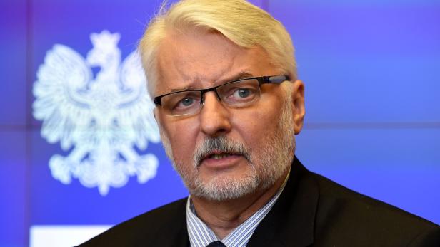 Ein Mann mit Brille und grauem Haar vor einem blauen Hintergrund mit einem Adler.