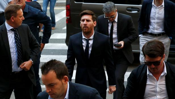 Lionel Messi in Anzug, umgeben von weiteren Personen.